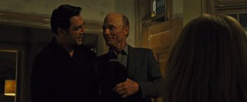 Movie still from “Mother!” (2017), directed by Darren Aronofsky – Two men standing next to each other in front of a wooden wall; Medium shot, Over the shoulder angle