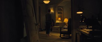 Movie still from “Mother!” (2017), directed by Darren Aronofsky – A person standing in a room with a lamp on; Wide shot, High angle