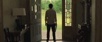 Movie still from “Mother!” (2017), directed by Darren Aronofsky – A man standing in front of an open front door; Wide shot, Low angle