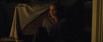 Movie still from “Mother!” (2017), directed by Darren Aronofsky – A woman sitting on a couch in a dark room; Medium shot, High angle