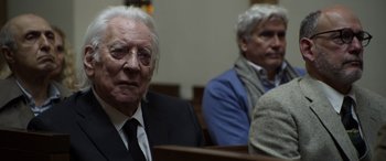 Movie still from “Mr. Harrigan's Phone” (2022), directed by John Lee Hancock – Two older men sitting in front of each other in a courtroom; Close Up shot, Over the shoulder angle