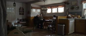 Movie still from “Mr. Harrigan's Phone” (2022), directed by John Lee Hancock – A group of people sitting at a table in a living room; Wide shot, Over the shoulder angle