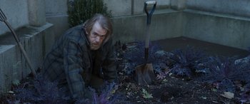 Movie still from “Mr. Harrigan's Phone” (2022), directed by John Lee Hancock – A man kneeling down next to a shovel in a garden; Medium shot, High angle