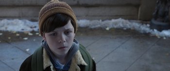 Movie still from “Mr. Harrigan's Phone” (2022), directed by John Lee Hancock – A young boy wearing a brown hat and a green jacket; Close Up shot, High angle