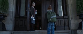 Movie still from “Mr. Harrigan's Phone” (2022), directed by John Lee Hancock – A man and a woman standing in front of a building; Medium shot, Low angle