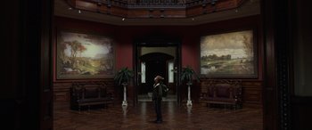 Movie still from “Mr. Harrigan's Phone” (2022), directed by John Lee Hancock – A man standing in a room with two paintings on the wall; Extreme Wide shot, Low angle