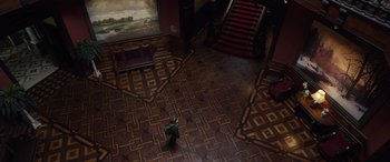 Movie still from “Mr. Harrigan's Phone” (2022), directed by John Lee Hancock – A person walking in a room with a painting on the wall; Extreme Wide shot, High angle