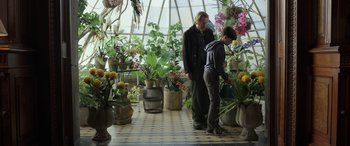 Movie still from “Mr. Harrigan's Phone” (2022), directed by John Lee Hancock – A woman and a boy looking at plants in a greenhouse; Wide shot, Over the shoulder angle
