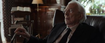 Movie still from “Mr. Harrigan's Phone” (2022), directed by John Lee Hancock – An older man in a suit and tie sitting in a chair; Close Up shot, Over the shoulder angle