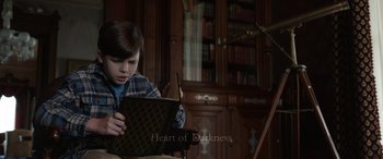 Movie still from “Mr. Harrigan's Phone” (2022), directed by John Lee Hancock – A young boy sitting in front of an open book; Medium shot, High angle