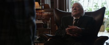 Movie still from “Mr. Harrigan's Phone” (2022), directed by John Lee Hancock – An old man sitting in a chair in front of a window; Close Up shot, Over the shoulder angle
