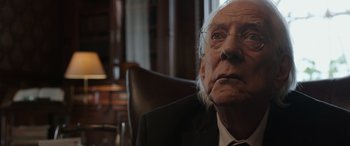 Movie still from “Mr. Harrigan's Phone” (2022), directed by John Lee Hancock – An old man wearing glasses and a suit and tie; Close Up shot, Over the shoulder angle