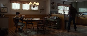 Movie still from “Mr. Harrigan's Phone” (2022), directed by John Lee Hancock – A dining room with a table , chairs and a chandelier; Wide shot, High angle