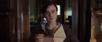 Movie still from “Mr. Harrigan's Phone” (2022), directed by John Lee Hancock – A young man holding an open envelope; Close Up shot, Over the shoulder angle