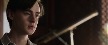 Movie still from “Mr. Harrigan's Phone” (2022), directed by John Lee Hancock – A young man's face in a dark room; Close Up shot, Over the shoulder angle