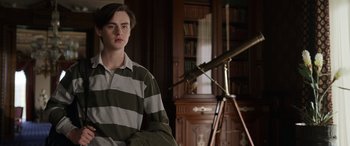 Movie still from “Mr. Harrigan's Phone” (2022), directed by John Lee Hancock – A young man in a striped shirt is in front of a telescope in a room; Medium shot, Low angle