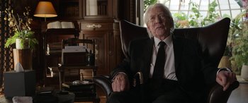 Movie still from “Mr. Harrigan's Phone” (2022), directed by John Lee Hancock – An older man in a suit and tie sitting in a chair; Medium shot, Over the shoulder angle