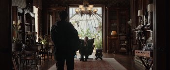 Movie still from “Mr. Harrigan's Phone” (2022), directed by John Lee Hancock – A man sitting in a chair in front of a large window; Wide shot, Over the shoulder angle