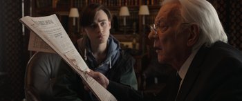 Movie still from “Mr. Harrigan's Phone” (2022), directed by John Lee Hancock – A man and a young boy looking at a newspaper; Close Up shot, Over the shoulder angle