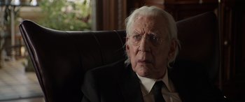 Movie still from “Mr. Harrigan's Phone” (2022), directed by John Lee Hancock – An old man wearing a suit and tie sitting in a chair; Close Up shot, Over the shoulder angle