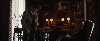 Movie still from “Mr. Harrigan's Phone” (2022), directed by John Lee Hancock – A man standing next to a bar in a library; Medium shot, Over the shoulder angle