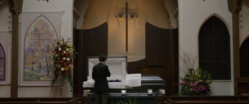 Movie still from “Mr. Harrigan's Phone” (2022), directed by John Lee Hancock – A man standing next to an empty casket; Wide shot, High angle