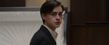 Movie still from “Mr. Harrigan's Phone” (2022), directed by John Lee Hancock – A man in a suit and tie looking at the camera; Close Up shot, Low angle