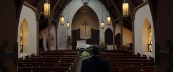 Movie still from “Mr. Harrigan's Phone” (2022), directed by John Lee Hancock – A man sitting in front of an altar in a church; Wide shot, Low angle