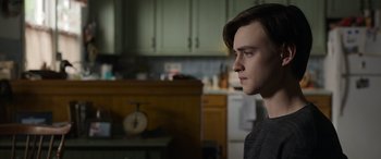 Movie still from “Mr. Harrigan's Phone” (2022), directed by John Lee Hancock – A young man is looking into the distance in a kitchen; Close Up shot, Over the shoulder angle