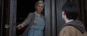 Movie still from “Mr. Harrigan's Phone” (2022), directed by John Lee Hancock – An older woman wearing an apron standing in front of a door; Medium shot, Over the shoulder angle