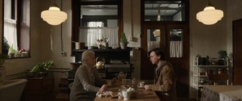 Movie still from “Mr. Harrigan's Phone” (2022), directed by John Lee Hancock – A man and a woman sitting at a wooden table; Medium shot, Over the shoulder angle