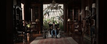 Movie still from “Mr. Harrigan's Phone” (2022), directed by John Lee Hancock – A person sitting in a chair in a living room; Wide shot, Low angle