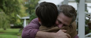 Movie still from “Mr. Harrigan's Phone” (2022), directed by John Lee Hancock – Two people hugging each other in a park; Close Up shot, Over the shoulder angle