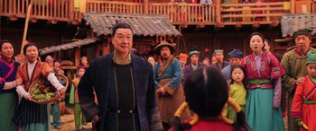 Movie still from “Mulan” (2020), directed by Niki Caro – An older man standing in front of a group of people; Medium shot, Over the shoulder angle