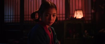 Movie still from “Mulan” (2020), directed by Niki Caro – A young girl with pigtails is looking at the camera; Close Up shot, Low angle