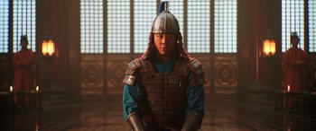 Movie still from “Mulan” (2020), directed by Niki Caro – A man wearing a helmet and armor in front of a window; Medium shot, Low angle