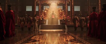 Movie still from “Mulan” (2020), directed by Niki Caro – A person standing in front of a throne in a room; Extreme Wide shot, High angle