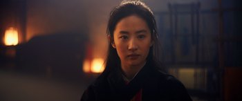 Movie still from “Mulan” (2020), directed by Niki Caro – A woman in a black jacket is looking at the camera; Close Up shot, Over the shoulder angle