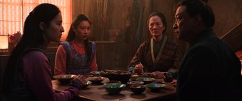 Movie still from “Mulan” (2020), directed by Niki Caro – Two women sitting at a table with bowls of food; Medium shot, Over the shoulder angle