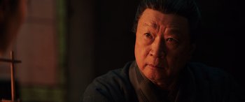 Movie still from “Mulan” (2020), directed by Niki Caro – An older asian man looking at the camera; Close Up shot, Low angle