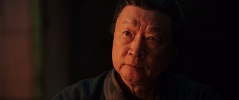 Movie still from “Mulan” (2020), directed by Niki Caro – An older man is looking at the camera; Close Up shot, Low angle