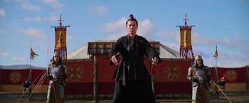 Movie still from “Mulan” (2020), directed by Niki Caro – A man in a black outfit holding a sword; Medium shot, Low angle
