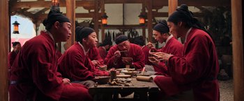 Movie still from “Mulan” (2020), directed by Niki Caro – A group of people sitting at a table eating food; Medium shot, Low angle