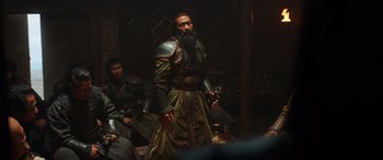Movie still from “Mulan” (2020), directed by Niki Caro – A man dressed in medieval clothing and armor; Medium shot, Low angle