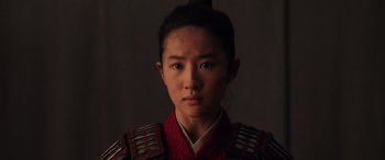 Movie still from “Mulan” (2020), directed by Niki Caro – A woman in a red and black outfit is posing for a picture; Close Up shot, Low angle