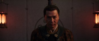 Movie still from “Mulan” (2020), directed by Niki Caro – A man wearing a hat with a bird on top of his head; Close Up shot, Low angle