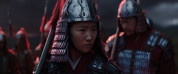 Movie still from “Mulan” (2020), directed by Niki Caro – A person wearing a helmet and a suit of armor; Close Up shot, Low angle