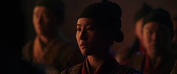 Movie still from “Mulan” (2020), directed by Niki Caro – A woman wearing a black hat is looking into the distance; Close Up shot, Over the shoulder angle