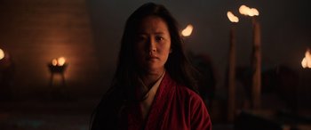 Movie still from “Mulan” (2020), directed by Niki Caro – A woman in a red robe standing in a dark room; Close Up shot, Low angle