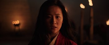 Movie still from “Mulan” (2020), directed by Niki Caro – A woman wearing a red robe is looking at the camera; Close Up shot, Low angle